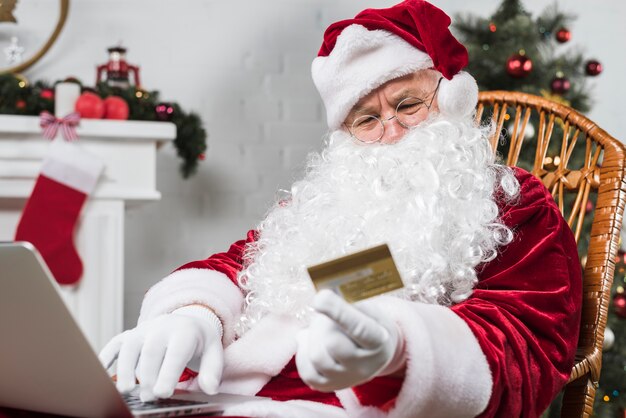 Kerstman die op schommelstoel met laptop en kaart zitten