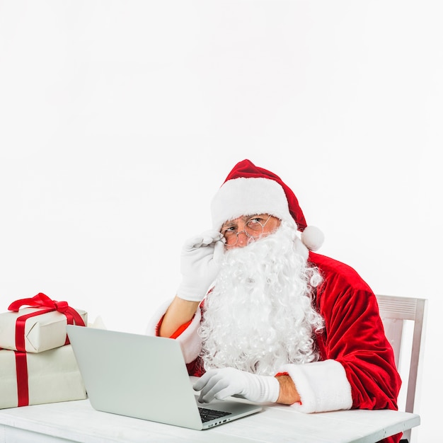 Gratis foto kerstman in hoed met behulp van laptop