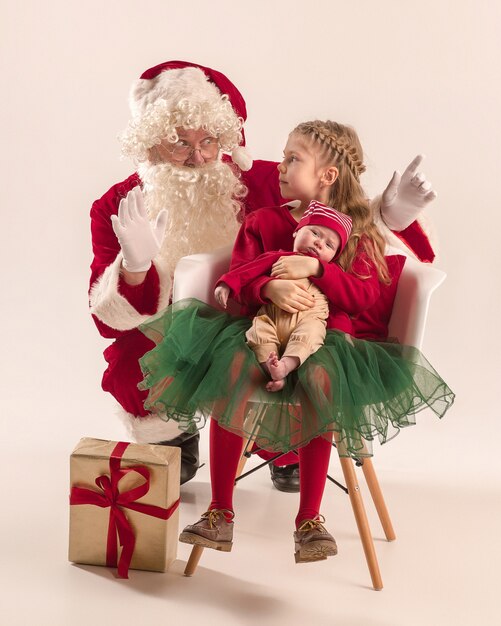 Kerstman in rood kostuum met een klein meisje en een baby op wit wordt geïsoleerd