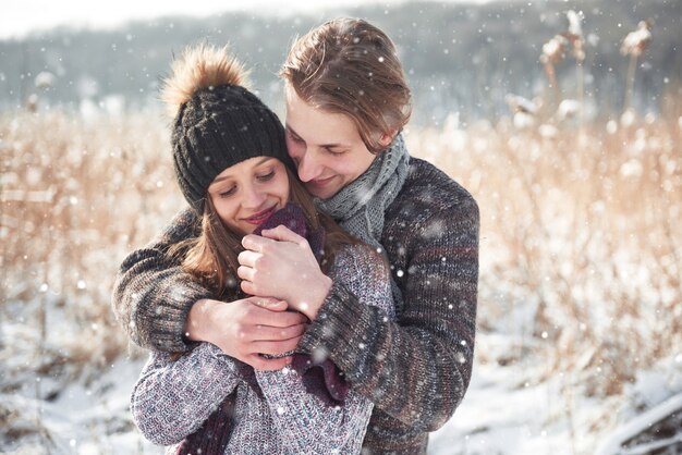 Kerstmis gelukkige paar verliefd omarmen in besneeuwde winter koud bos