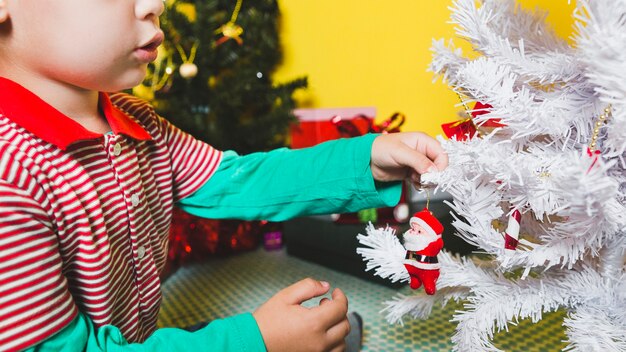 Kerstmisconcept met jong geitje die boom verfraaien