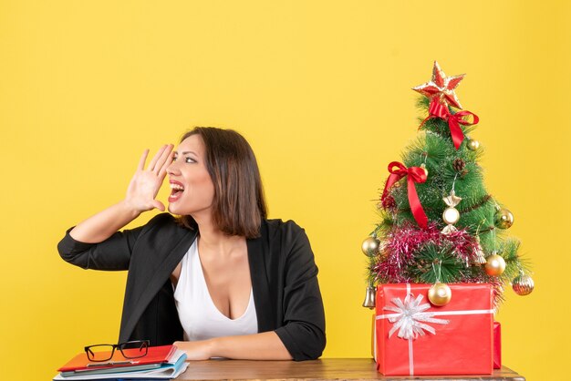 Kerstsfeer met jonge mooie vrouw die iets roept door de rechterkant op kantoor te kijken