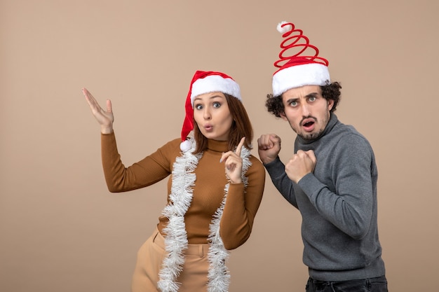 kerststemming met opgewonden koel tevreden verrast mooi paar dat rode kerstman-hoeden draagt die hierboven wijzen