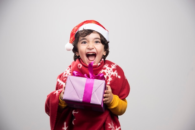 Kersttijd met een gelukkig kind dat een geschenkdoos vasthoudt Gratis Foto