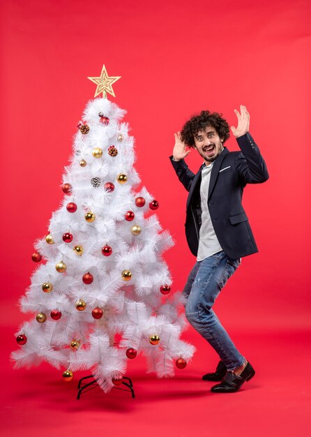 kerstviering met gelukkig grappige jongeman dansen en staan in de buurt van de kerstboom