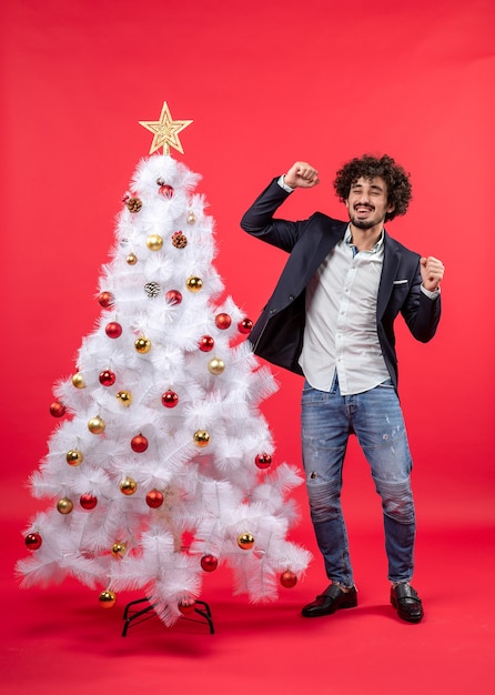 kerstviering met jonge gelukkig opgewonden grappige man dansen in de buurt van de kerstboom