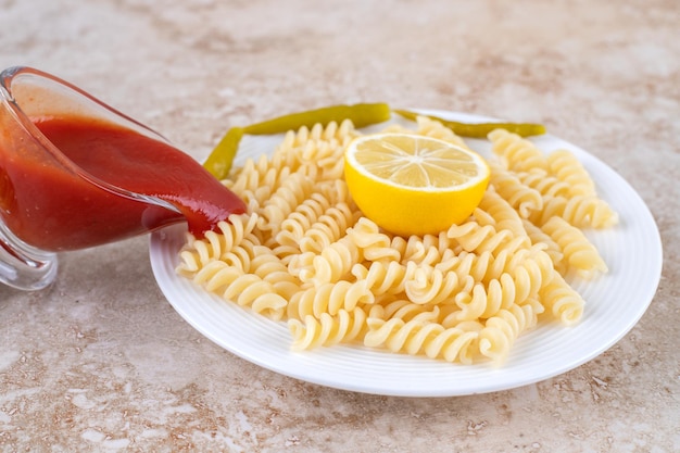 Ketchup wordt gegoten over een schotel pasta op een marmeren oppervlak