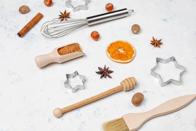 Keuken bakken gebruiksvoorwerpen met kruiden voor koekjes en cookie cutters op lichte ondergrond