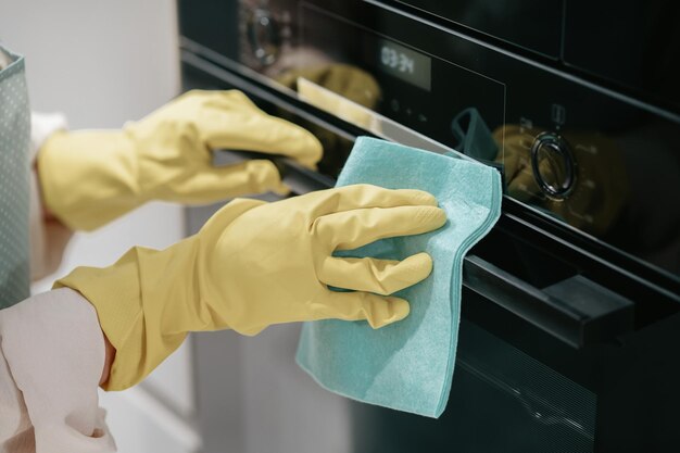 Keuken werk. Jonge donkerharige vrouw die keukenapparatuur schoonmaakt