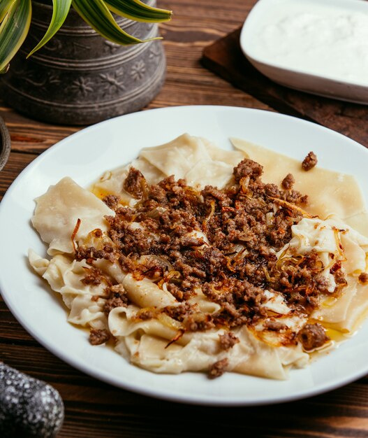 Khinkali in de vorm van bladeren met gevulde vlees en gebakken uien op tafel