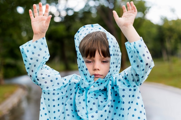 Kid draagt een blauwe regenjas met stippen