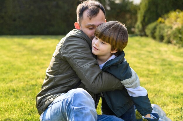 Kid en vader knuffelen op gras