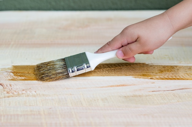 Gratis foto kid hand varnishing een houten plank met penseel