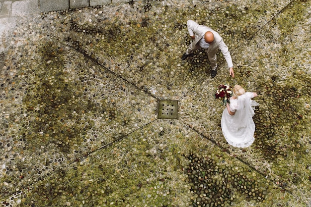 Kijk van bovenaf naar bruid en bruidegom die over de achtertuin lopen