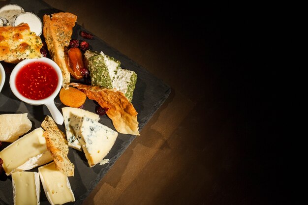 Kijk vanaf boven bij zwarte schotel met blauwe kaas, camembert, brie