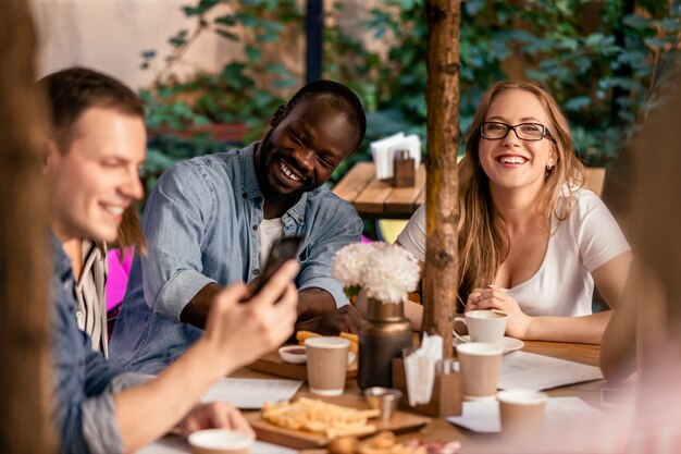 Kijken naar grappige video's op internet met collega's in het café op het terras met lekker eten