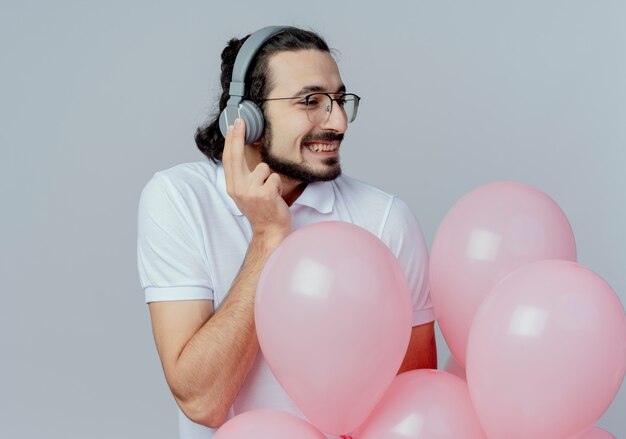 kijken naar kant lachende knappe man met bril en koptelefoon met ballonnen