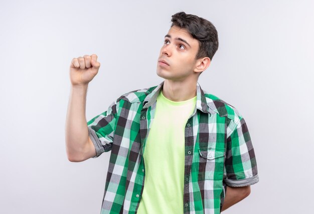 Kijkend naar kant blanke jonge man met groen shirt vuist opheffen op geïsoleerde witte muur