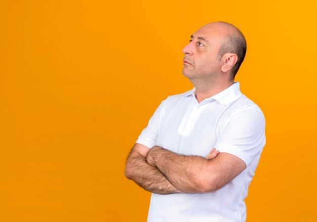 Kijkend naar kant casual volwassen man handen kruisen geïsoleerd op gele muur met kopie ruimte