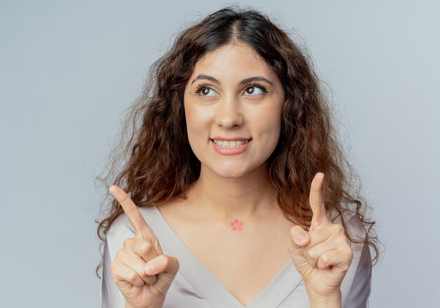 Kijkend naar kant tevreden jonge mooie vrouwelijke kantoormedewerker wijst naar boven geïsoleerd op een witte achtergrond