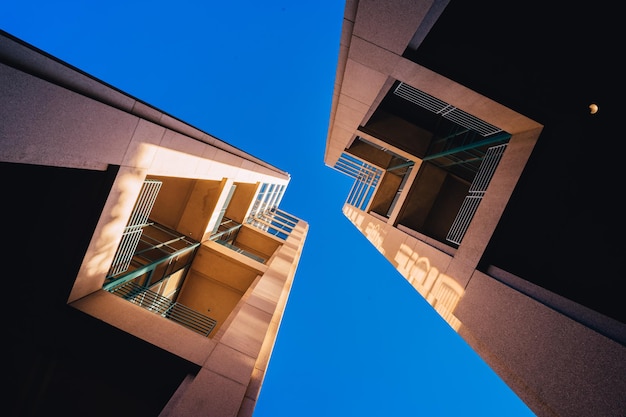 Gratis foto kikkerperspectief van architectonische tweelinggebouwen tegen een heldere blauwe lucht