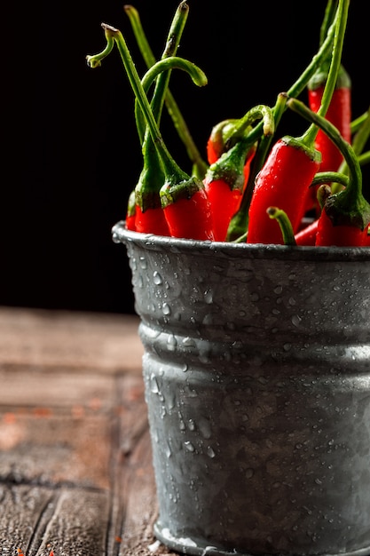 Kille rode paprika's in een mini-emmer close-up op stenen tegels en zwart