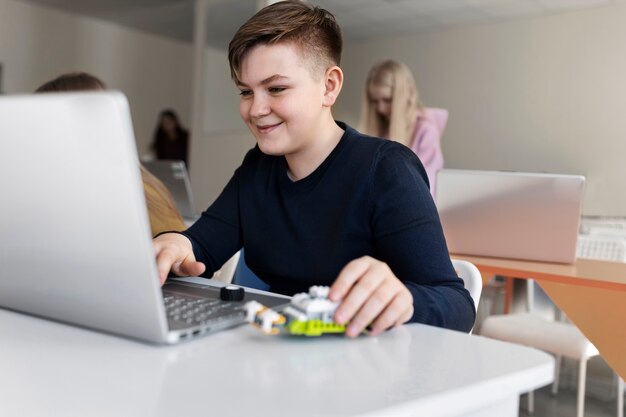 Kind dat een laptop en elektronische onderdelen gebruikt om een robot te bouwen