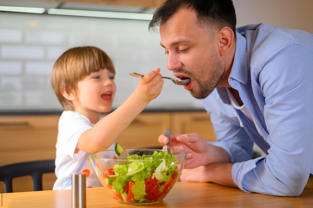 Kind dat zijn vadersalade geeft om te eten