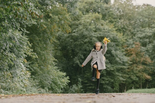 Kind in een herfstpark. Kid in een grijze jas.