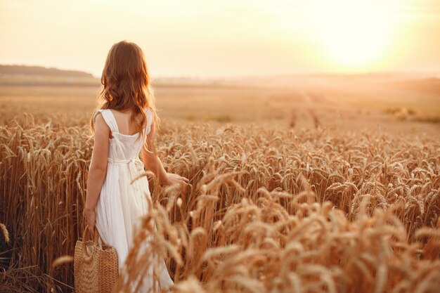 Kind in een zomer tarweveld. Klein meisje in een schattige witte jurk.