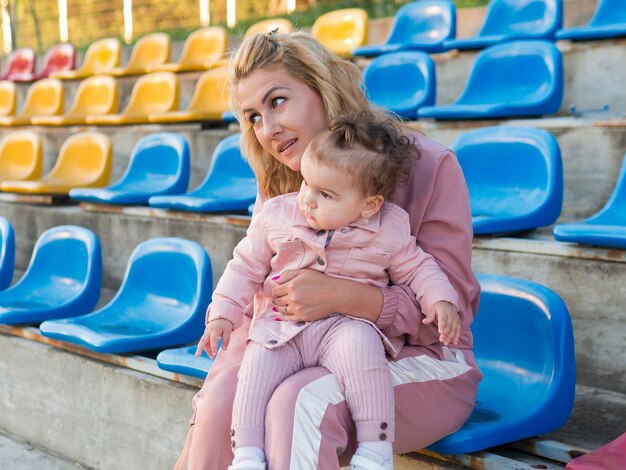 Kind in roze kleding en moeder zittend op een stoel