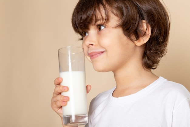 kind jongen zoete witte volle melk drinken op roze