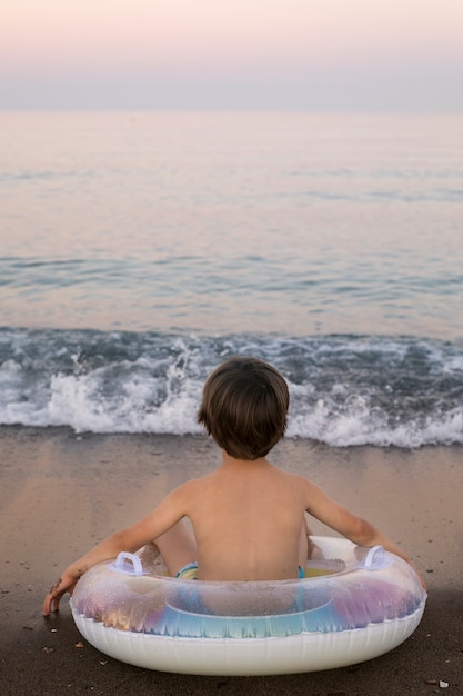 Gratis foto kind met drijver aan de kust