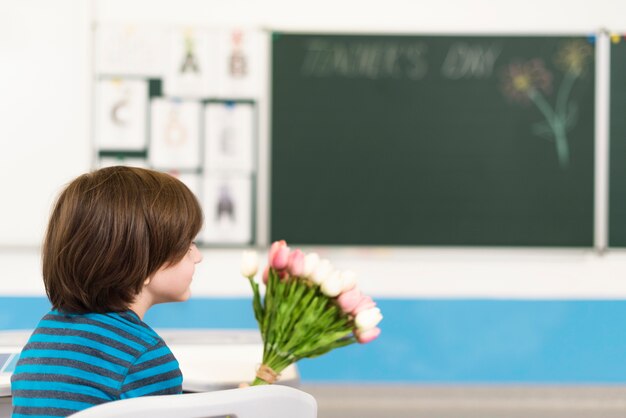 Kind met een boeket bloemen voor zijn leraar