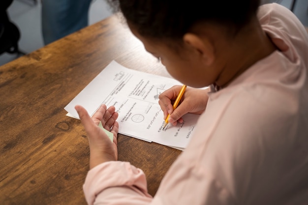 Gratis foto kind met een hoge hoek bedriegt bij schooltest