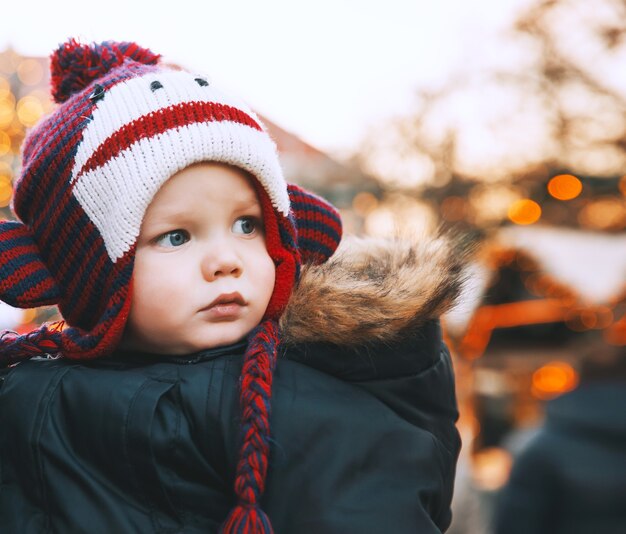 Kind met grappige hoed brengt wintervakanties door met familie in het oude centrum van klagenfurt, oostenrijk Premium Foto
