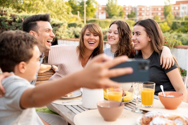 Kind neemt selfie van familie die samen buiten luncht