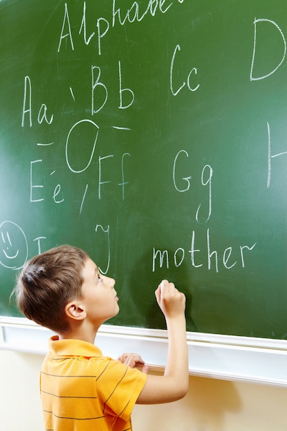 Kind schrijven met een krijt op een schoolbord