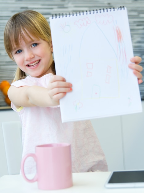 Gratis foto kind tekenen met kleurpotloden, zitten aan tafel in de keuken thuis