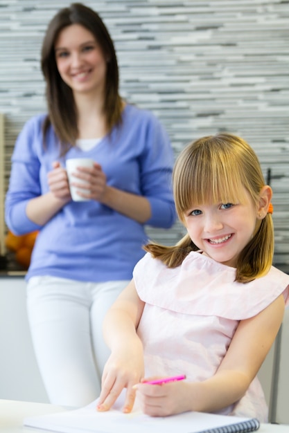 Kind tekenen met krijtjes met haar moeder thuis