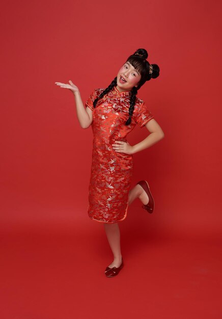 kinderen Aziatisch meisje in rood traditionele cheongsam qipao met gebaar van welkom Chinees nieuwjaar 2024