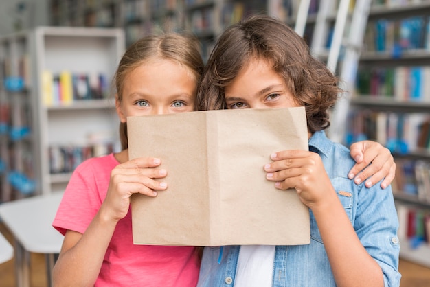 Kinderen bedekken hun gezicht met een boek