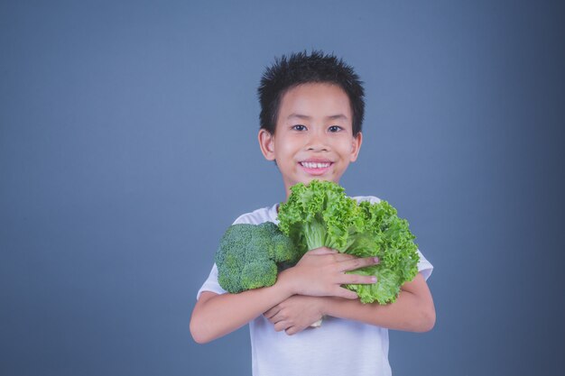 Kinderen die groenten op een grijze achtergrond houden.