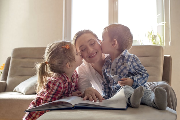 Kinderen die hun gelukkige moeder kussen terwijl ze een boek leest