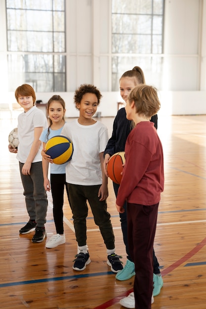 Kinderen houden ballen vast in de sportschool full shot