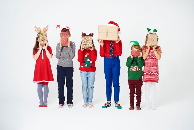 Kinderen houden kerstcadeautjes voor hun gezicht