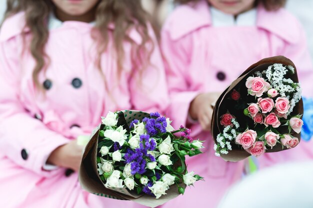 Kinderen houden roze en violette boeketten
