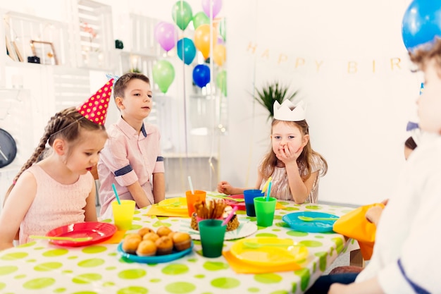 Kinderen in gekleurde doppen zitten aan tafel