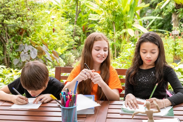 Kinderen jongen en meisje huiswerk en tekenen samen in de tuin thuis