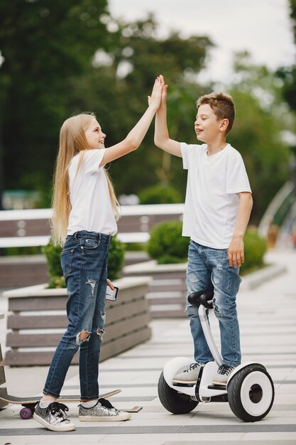 Kinderen leren hoverboard rijden in een park op zonnige zomerdag